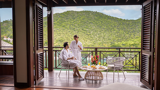 Two adults enjoying a meal on the patio of a hotel with their hotel robes on.