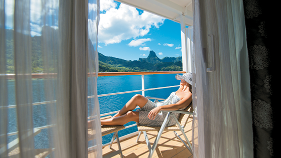 Woman sitting on cruise ship balcony relaxing in the sun.